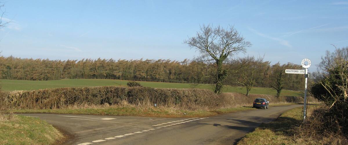 A rural road with a sign indicating Shutford 3 1/2 miles ahead.