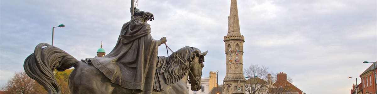 Eine Statue eines Mannes zu Pferde auf einem öffentlichen Platz, im Hintergrund ein Kirchturm.