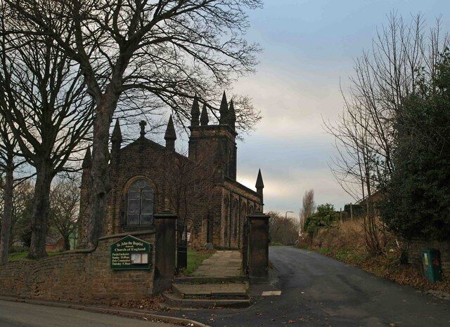 A church with a prominent steeple and a signboard.