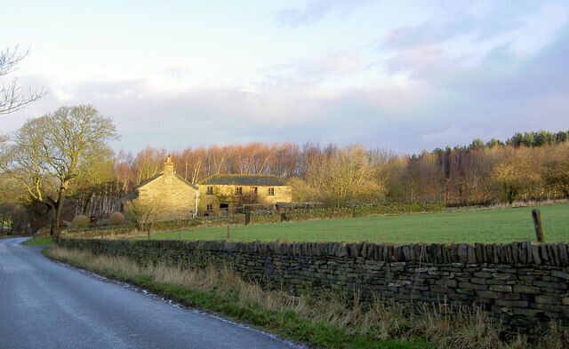 A stone wall, a rural road, and a stone building in a countryside setting.