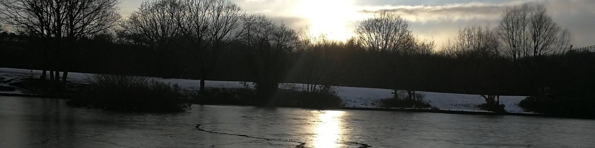 The sun over the pond in Dearne Valley park on a snowy afternoon