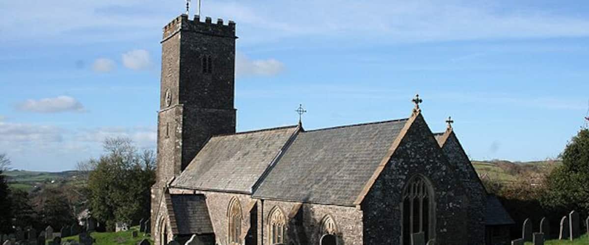 A church with a tall tower and a stone building with a sloped roof.