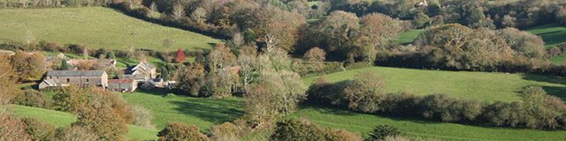 Loxhore: near Hill The farm on the left is Coombe: it has a restored, working, waterwheel. With Bratton Fleming village on the hill in the distance. Looking east-north-east