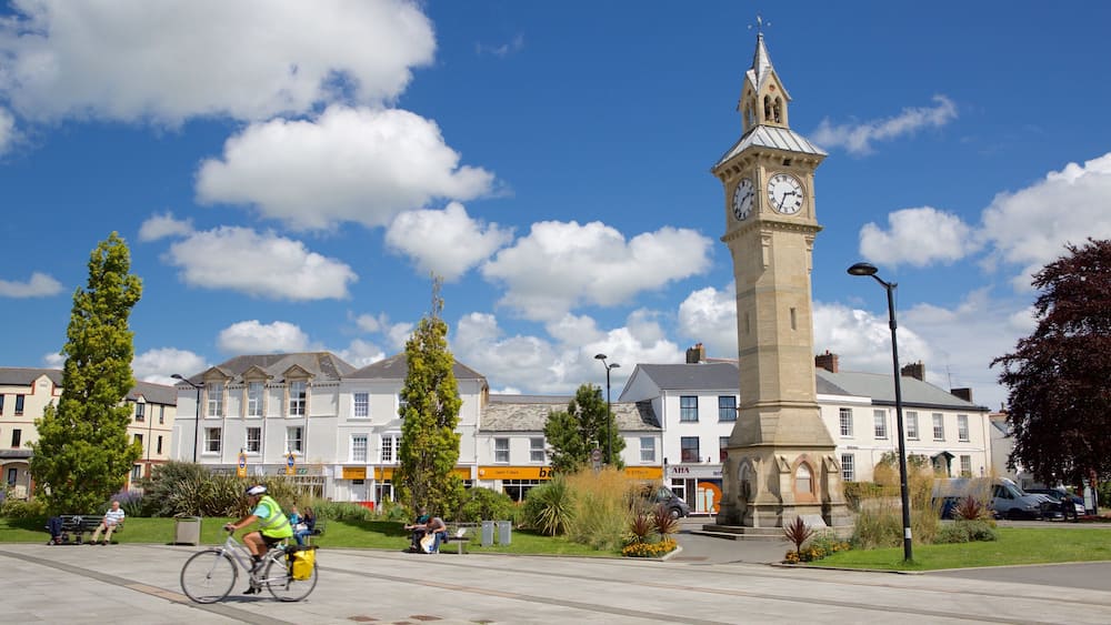 Ein Stadtplatz mit einem Glockenturm, Gebäuden und einem Radfahrer.