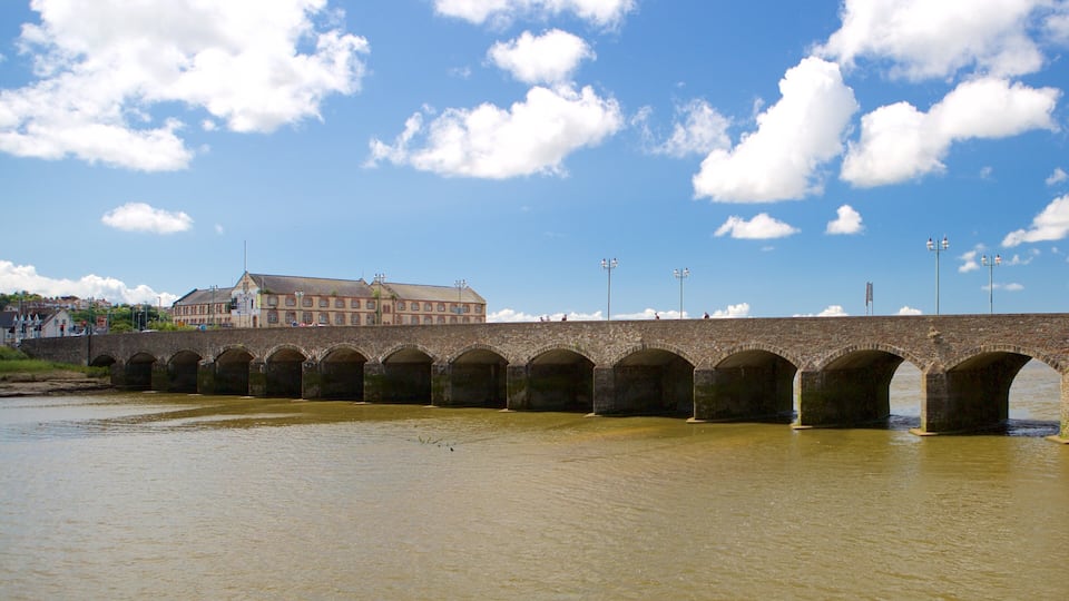 A stone bridge over a river with a building in the background.
