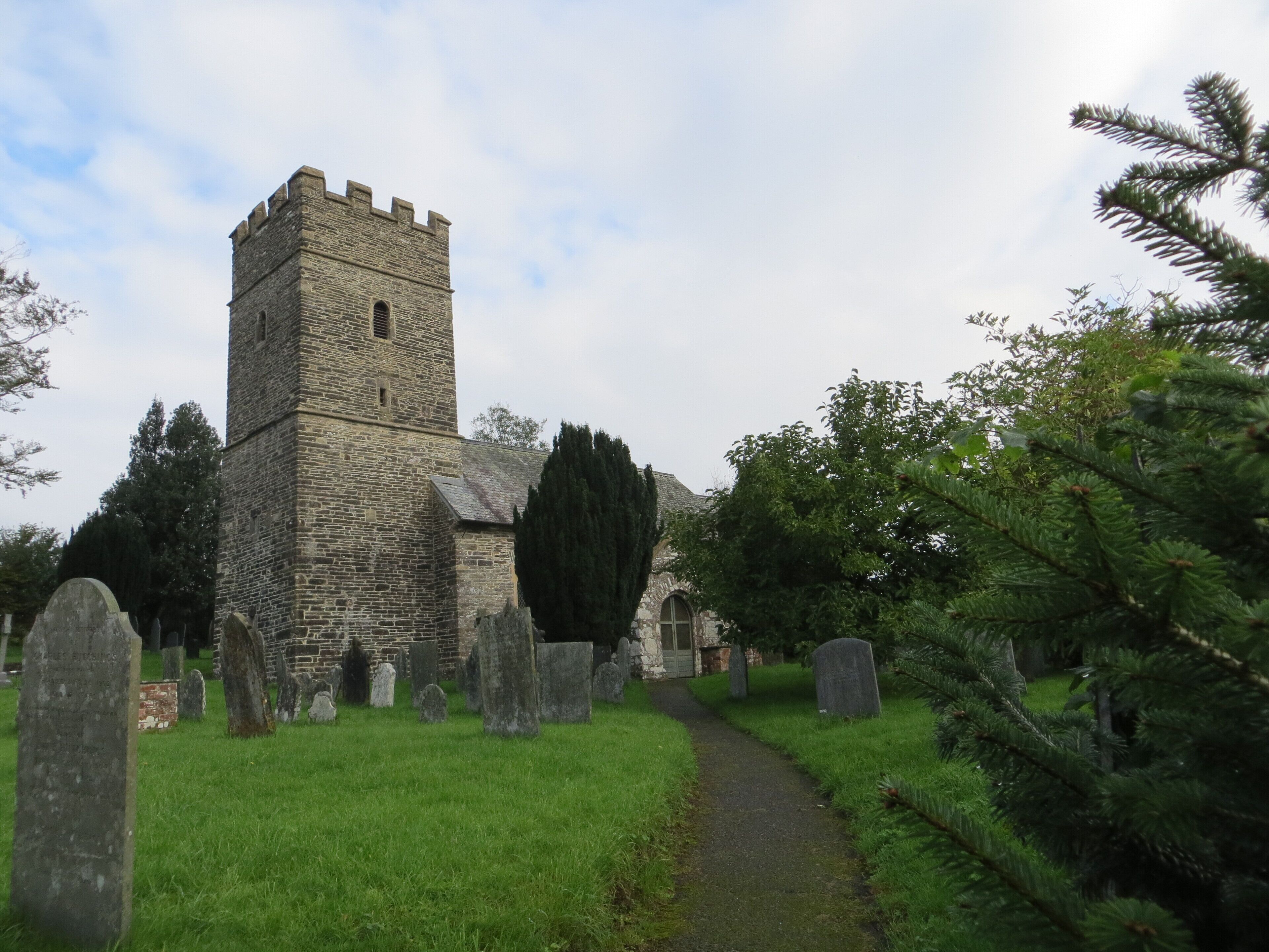 A stone church with a tower and a graveyard.