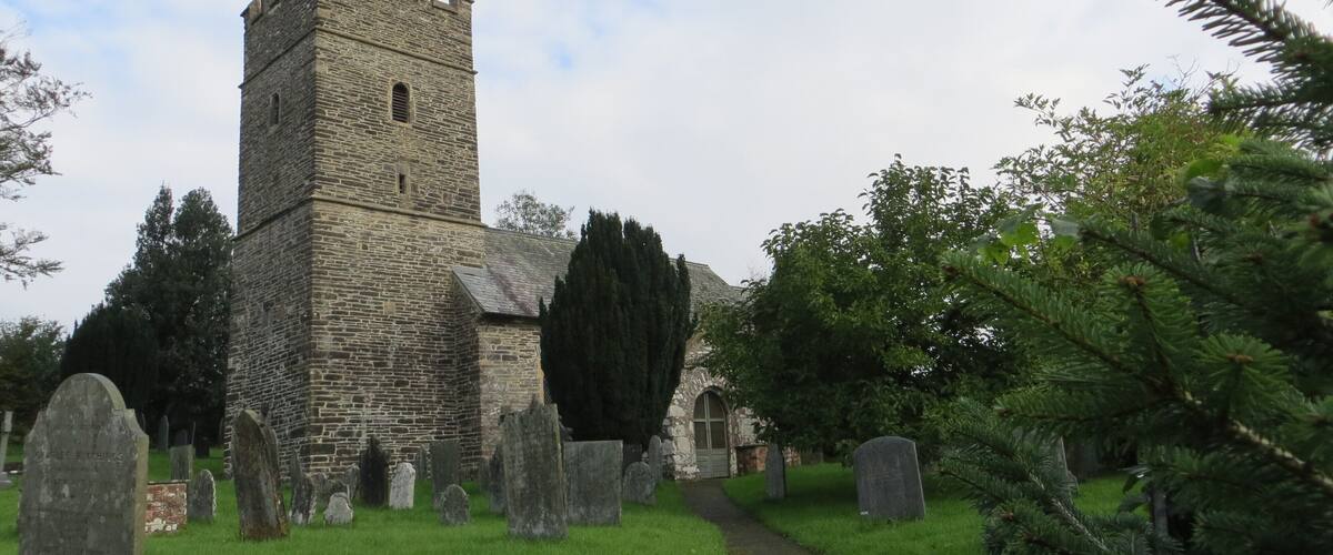 A stone church with a tower and a graveyard.