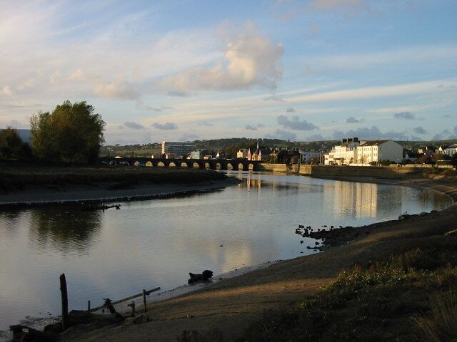 A river with a bridge, buildings, and a tree.