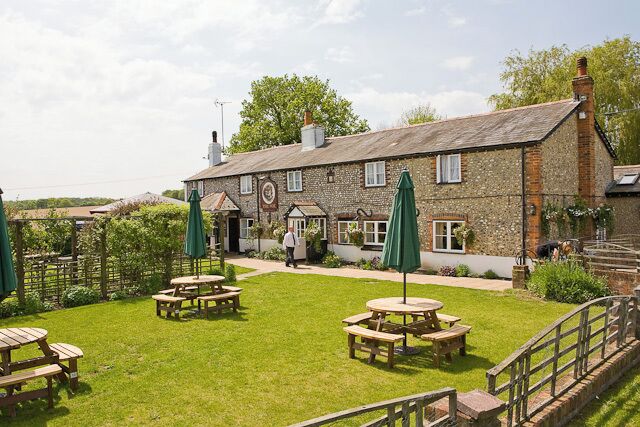 A stone building with a garden patio, outdoor seating, and a clock.