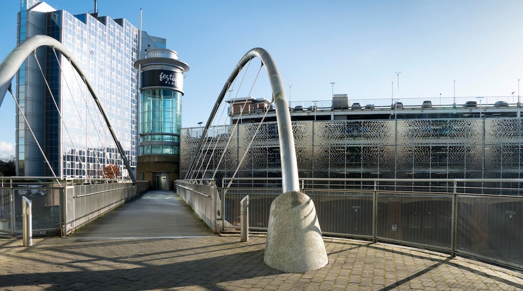 A pedestrian bridge with a glass facade and a metal arch structure.
