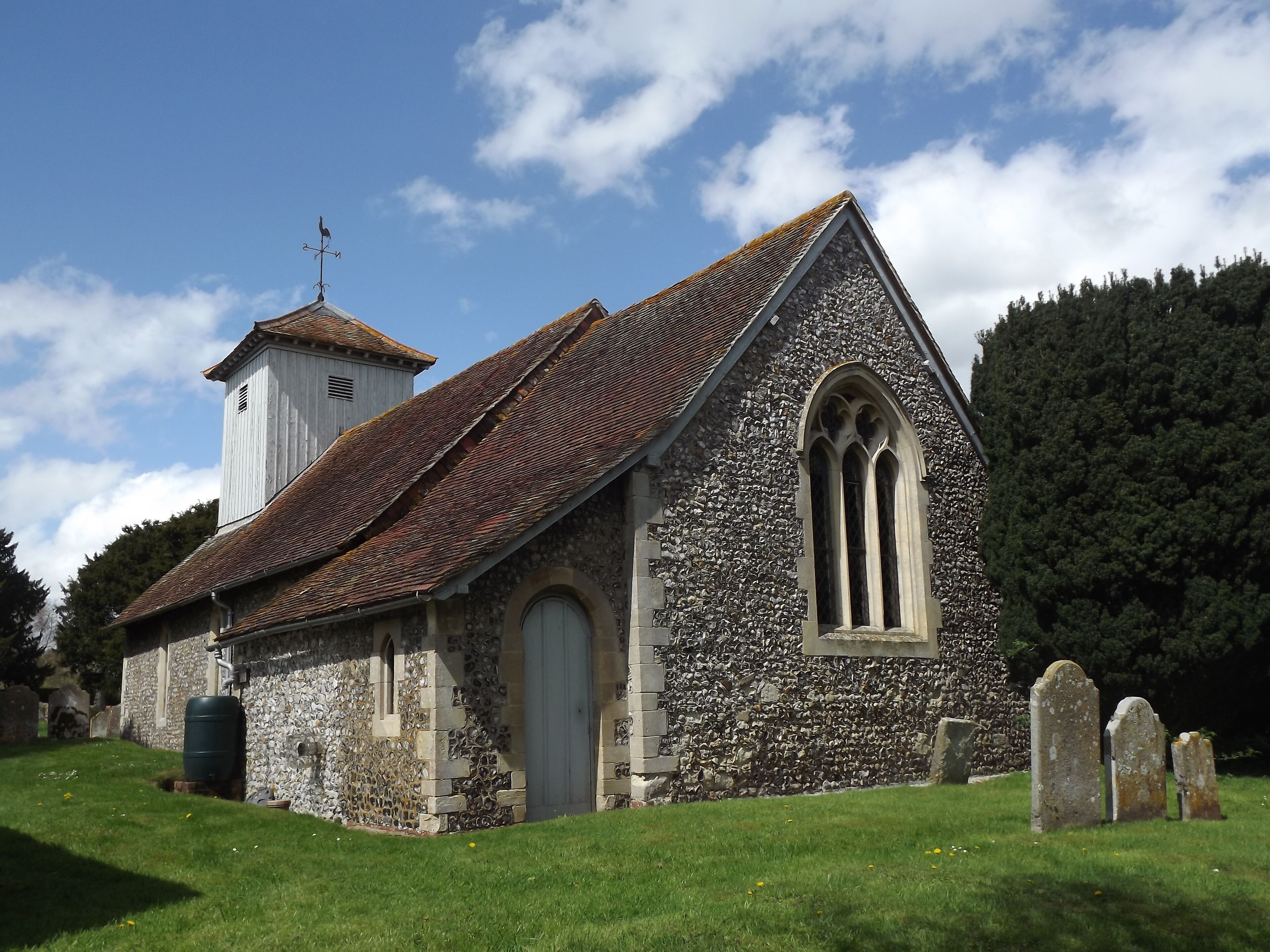 A stone church with a bell tower and a cemetery.