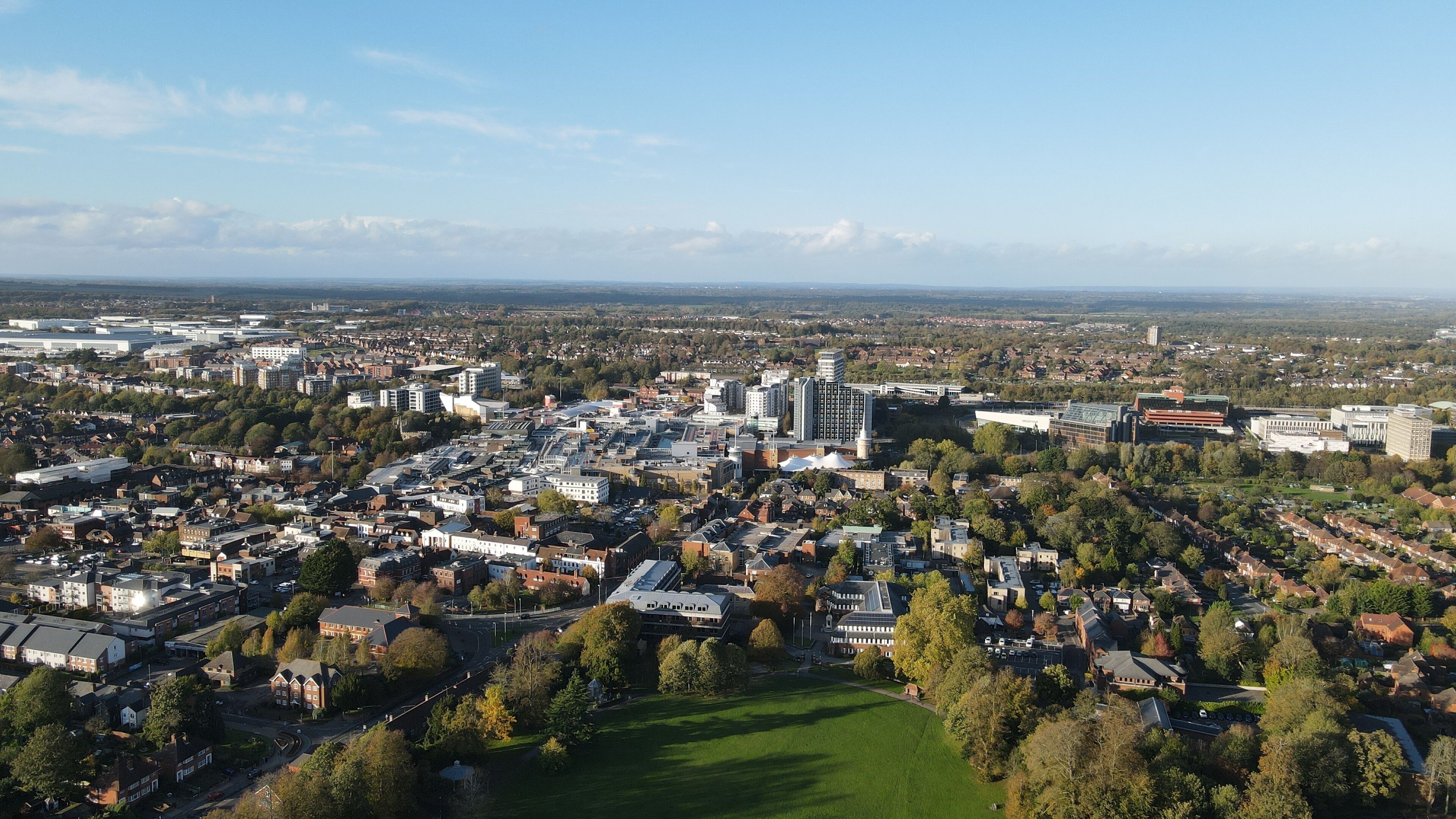 An aerial view of a city with dense urban development, green spaces, and a mix of residential and commercial buildings.