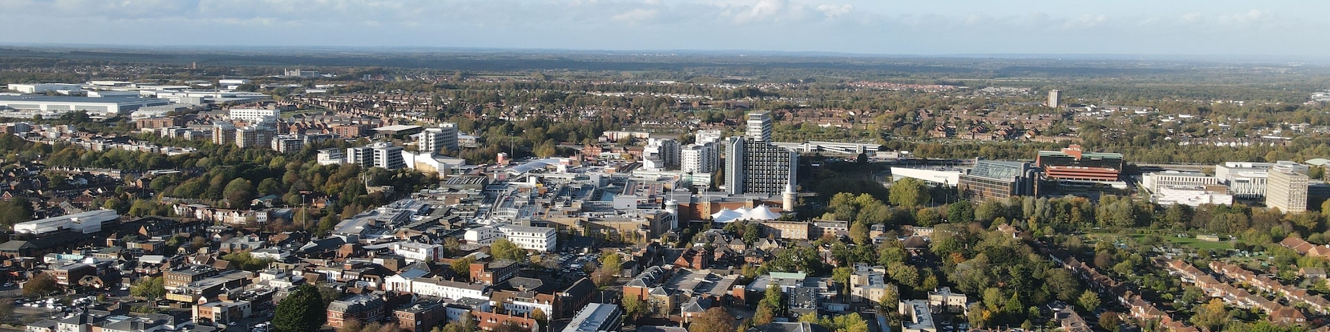 An aerial view of a city with dense urban development, green spaces, and a mix of residential and commercial buildings.