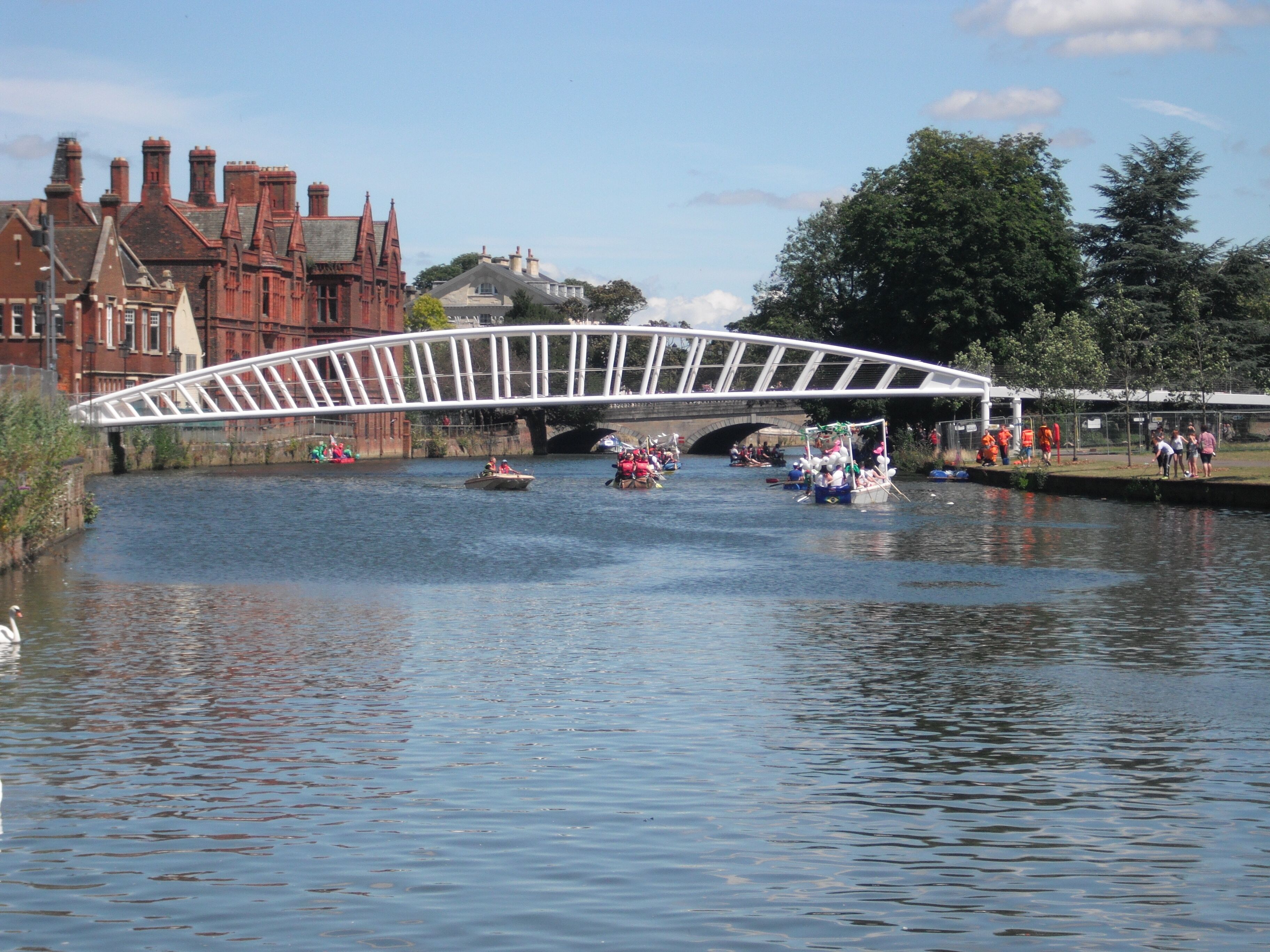 A river with boats, a white bridge, and red buildings.