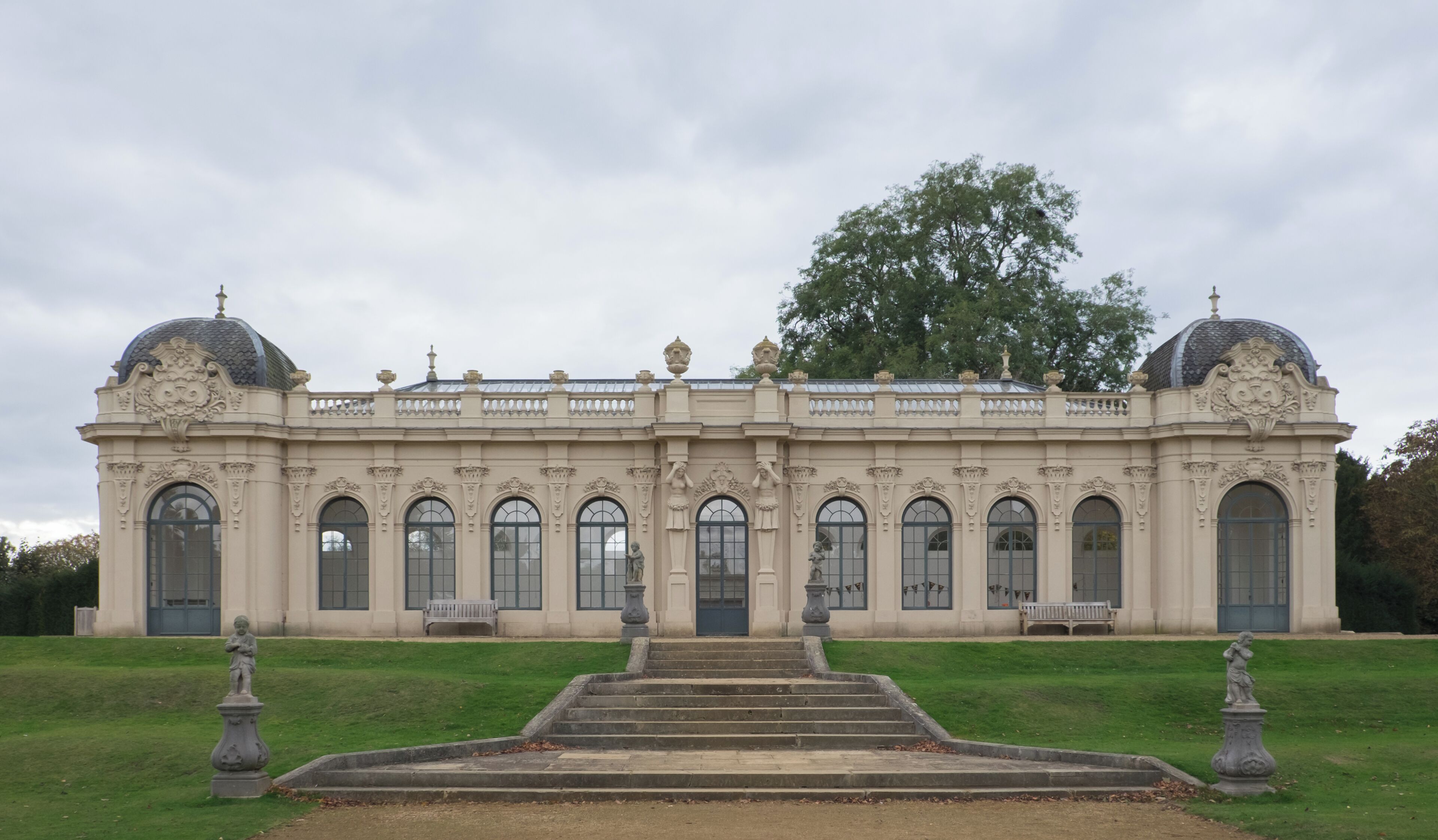 A grand neoclassical building with symmetrical architecture, large arched windows, and two prominent domes.