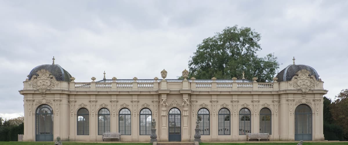 A grand neoclassical building with symmetrical architecture, large arched windows, and two prominent domes.
