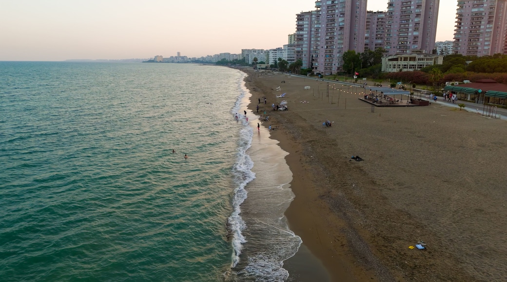 Mersin, Turkey. Low flight over wave surge line on beach with first line apartment buildings and relaxing people. Mezitli coastline.. Aerial View