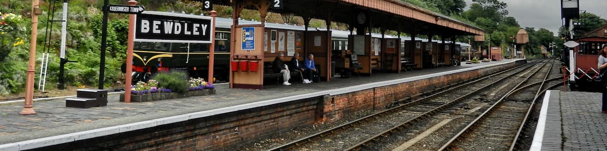 Ein Bahnhof mit überdachter Bahnsteig, Gleisen und einem Schild mit der Aufschrift 'Bewdley'.