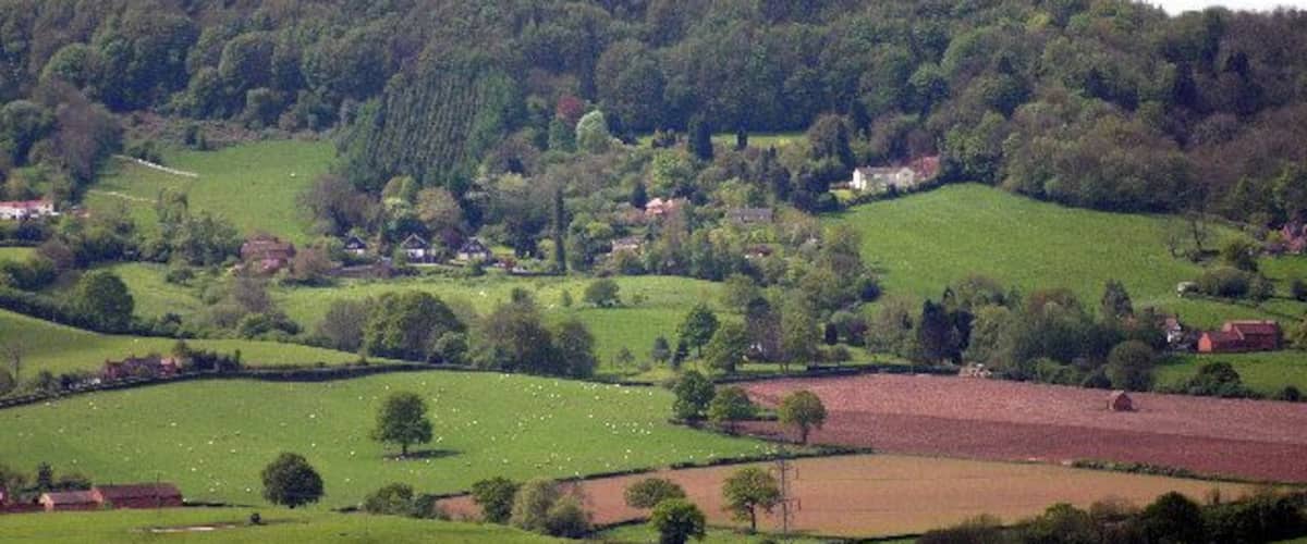 Des collines ondulantes, un village et une montagne boisée.