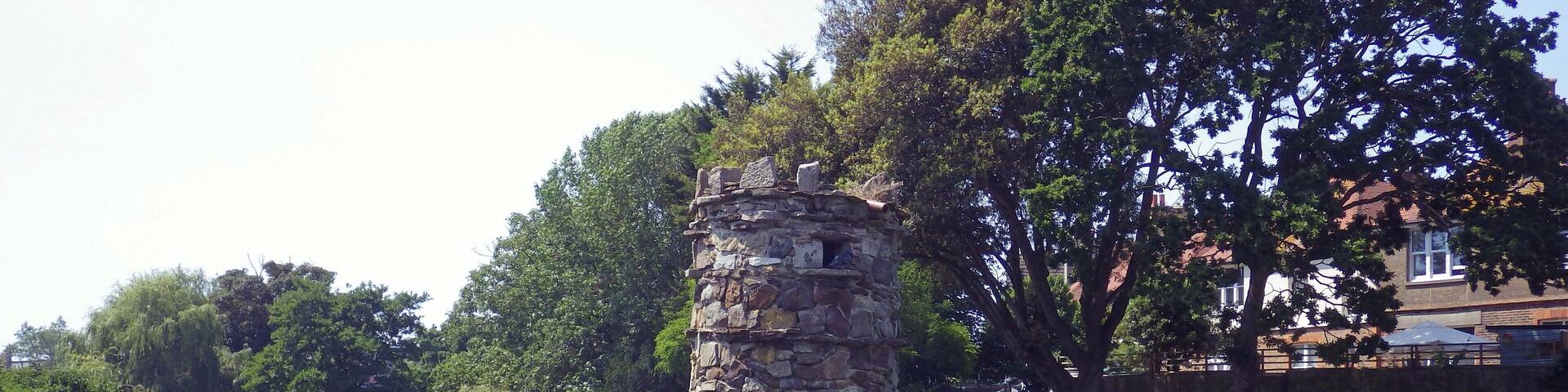 A stone tower surrounded by lush greenery and a calm river.