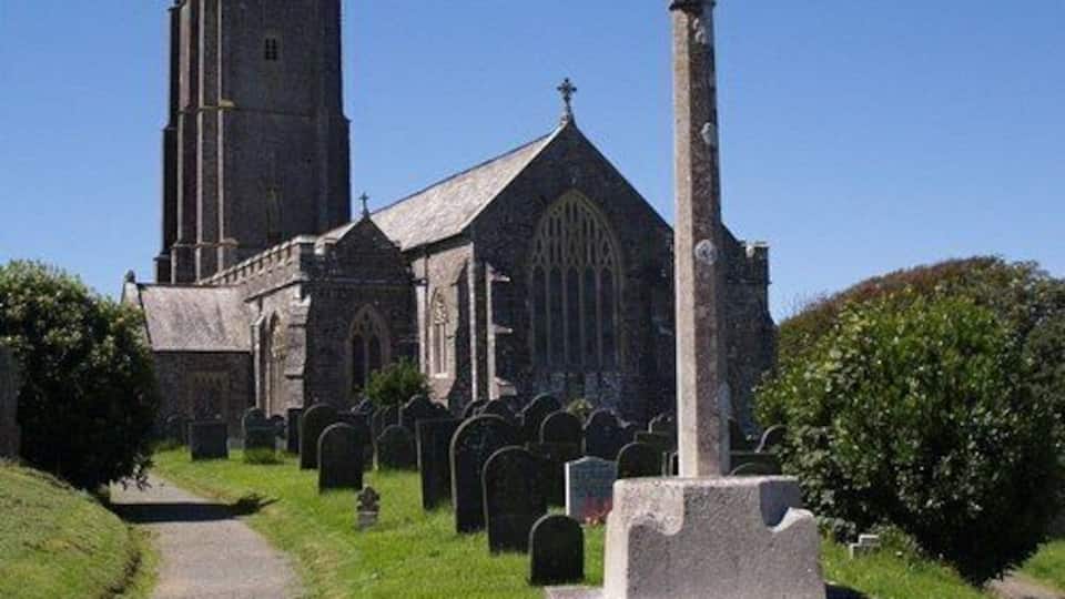 A church with a tall tower and a gravestone monument in the foreground.