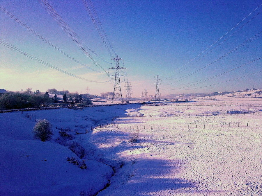 Paisaje nevado con líneas eléctricas y torres de transmisión.