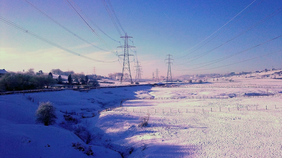 A snow-covered landscape with power lines and transmission towers.