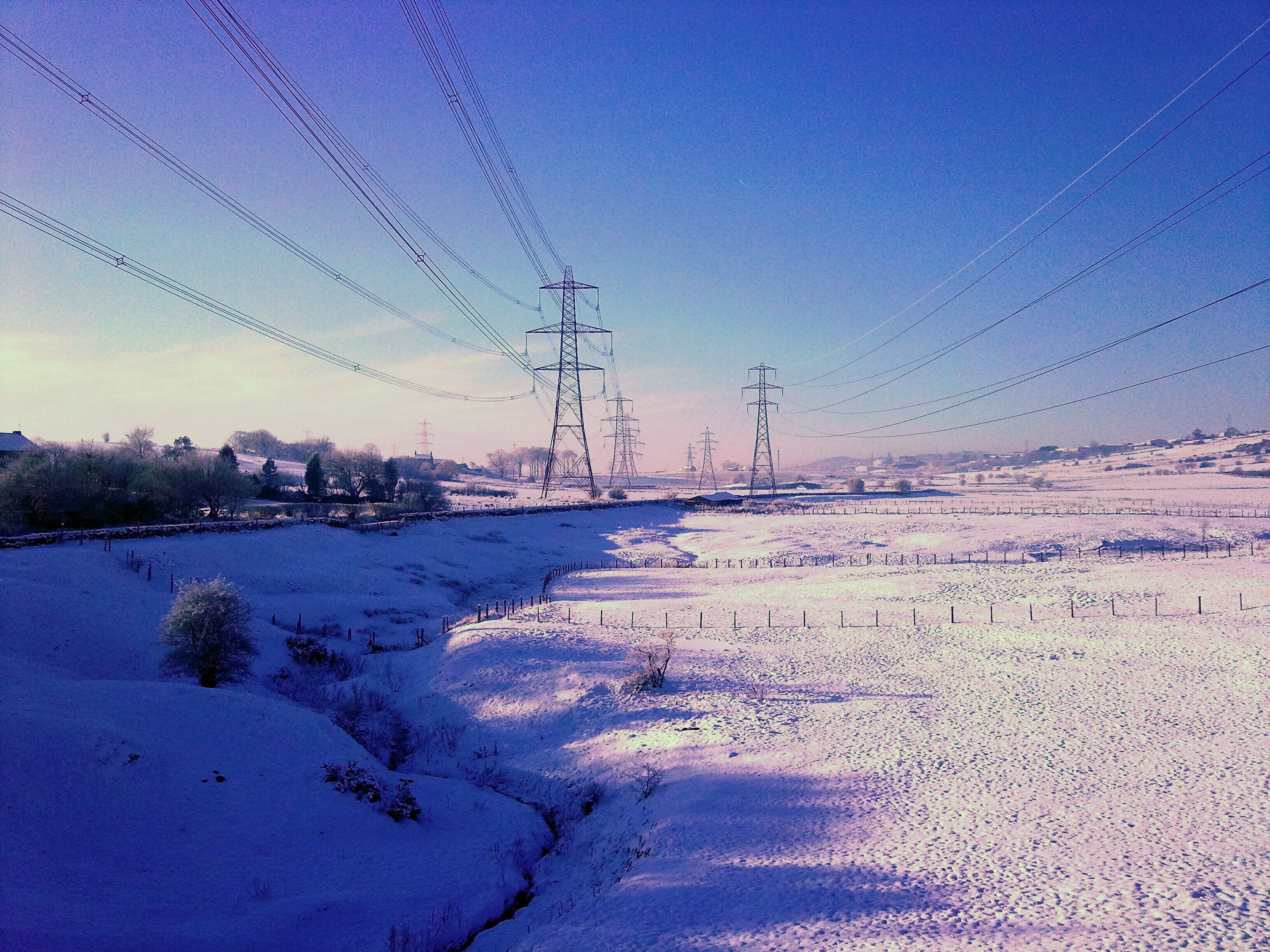 A snow-covered landscape with power lines and transmission towers.