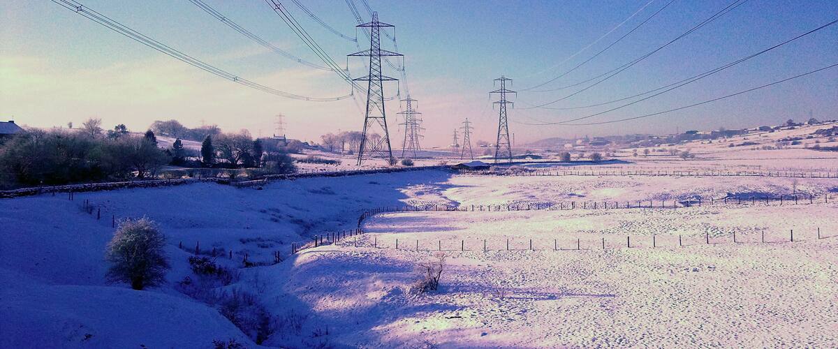A snow-covered landscape with power lines and transmission towers.