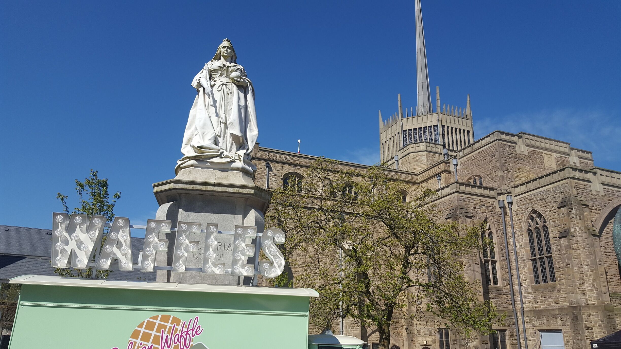 A statue in front of a church with a clock tower.