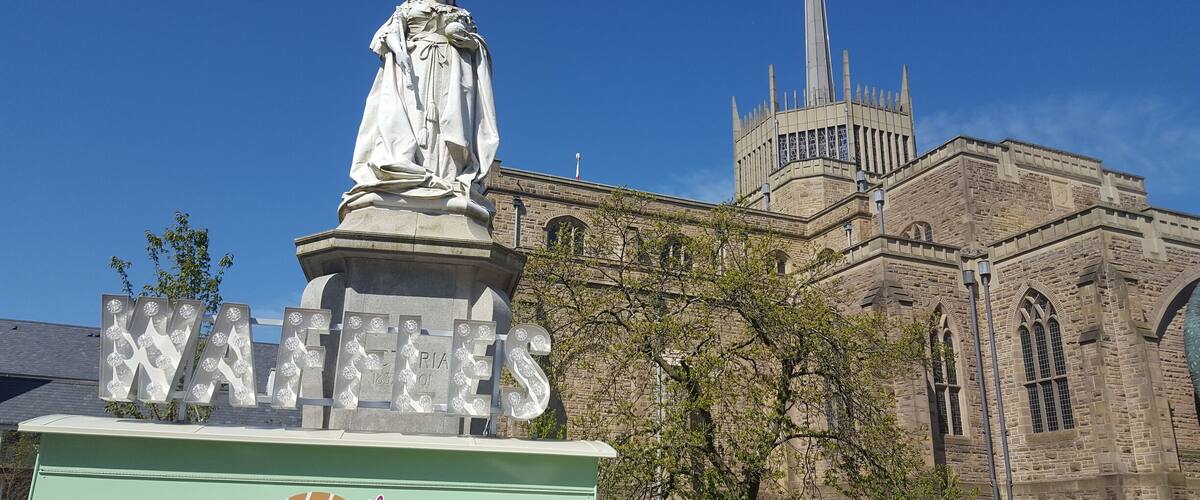 A statue in front of a church with a clock tower.