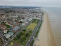 An aerial view of a coastal town with a beach, residential areas, and a large stadium.