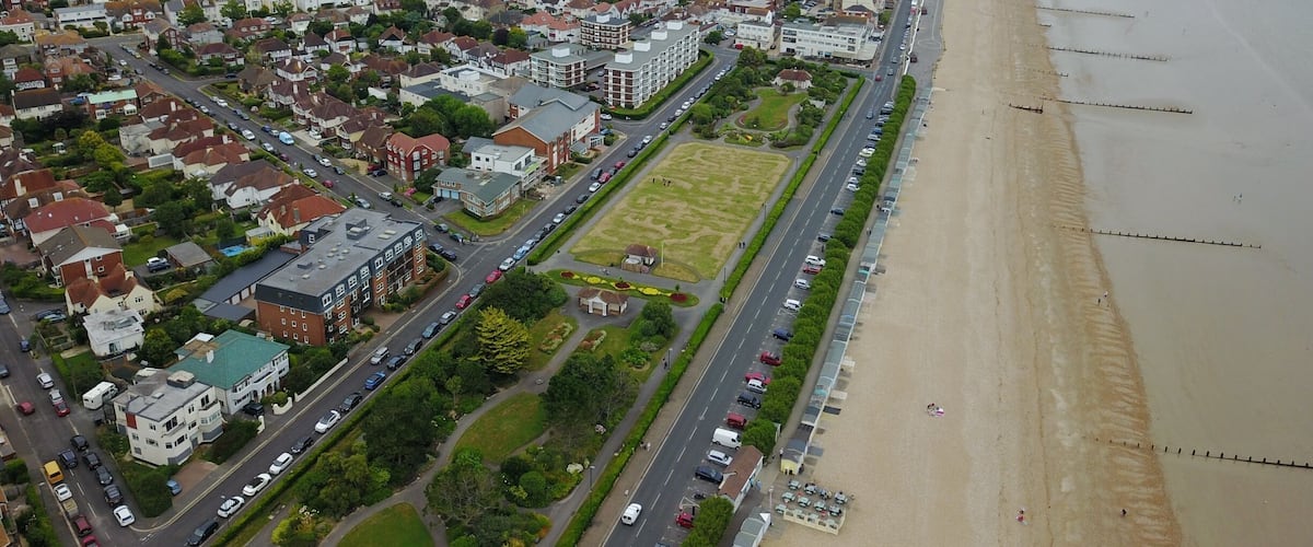 An aerial view of a coastal town with a beach, residential areas, and a large stadium.