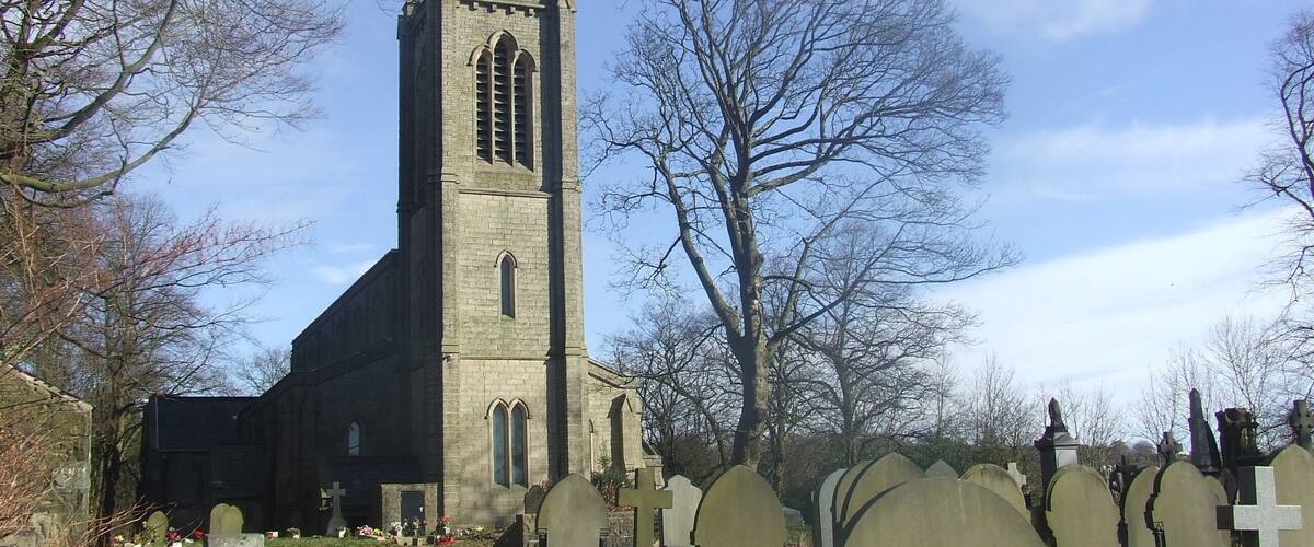 A church with a tall tower and a cemetery with headstones.