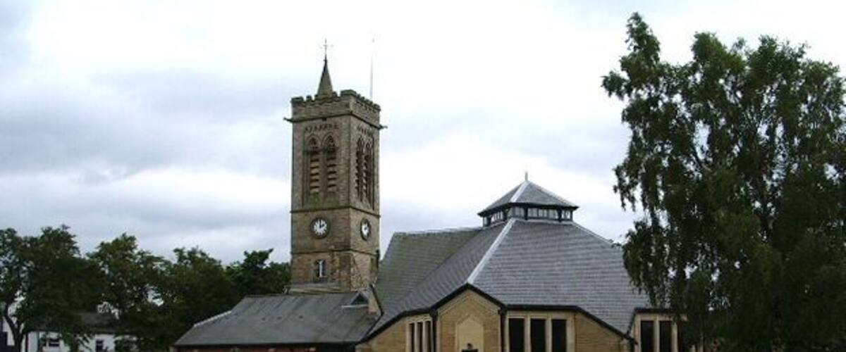 A church with a clock tower and a cemetery with gravestones.