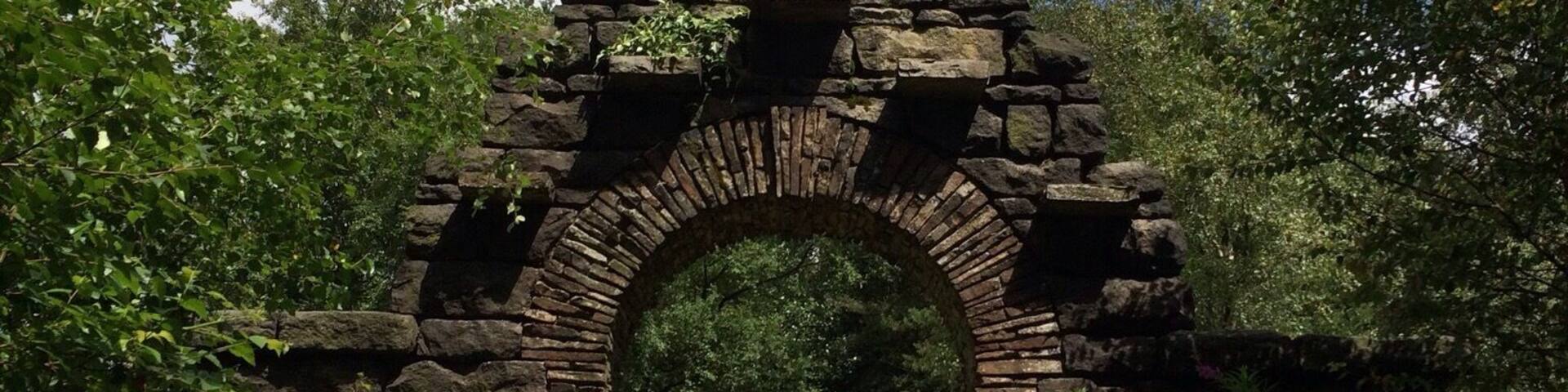 A stone archway leading through a forested area.
