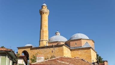 A mosque with a tall minaret and two domes.