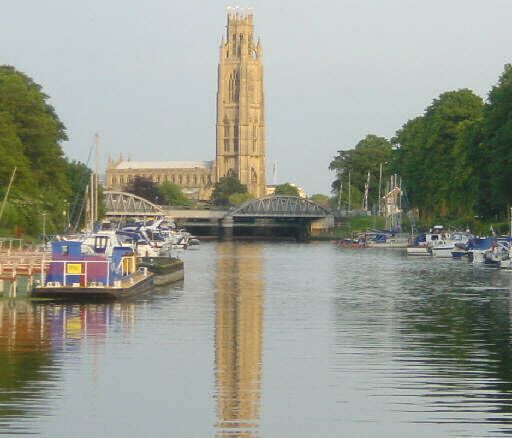 A river with boats, a bridge, and a tall building in the background.