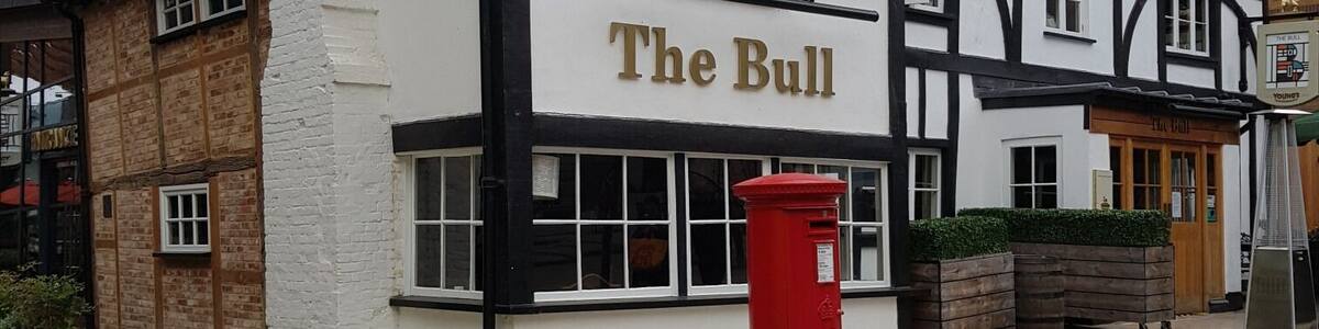 Ein traditionelles Pub namens "The Bull" mit einem roten Briefkasten davor.