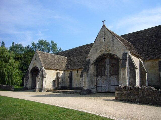 A historic church with a cross on the roof, large arched windows, and a gravel driveway.