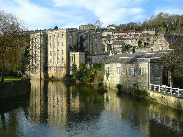 A historic building with a large reflective water body in front.