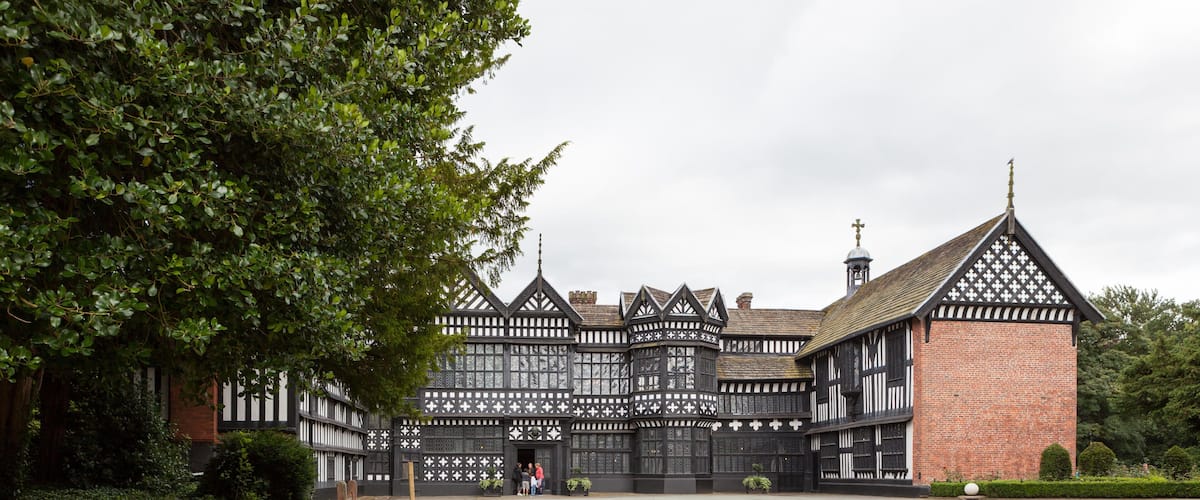 A Tudor-style building with a brick tower and timber framing.