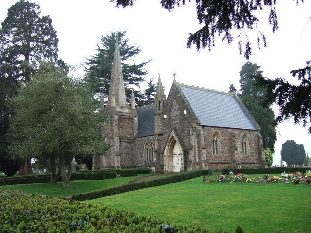 A church with a tall spire, surrounded by a well-manicured lawn and trees.