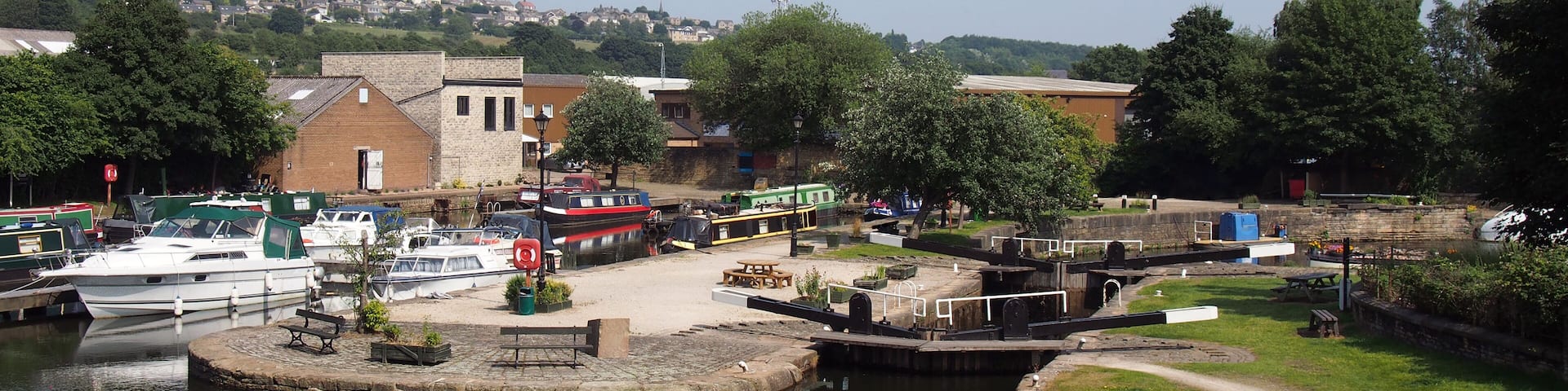 A calm harbor with boats docked, a small island with a dock, and buildings in the background.