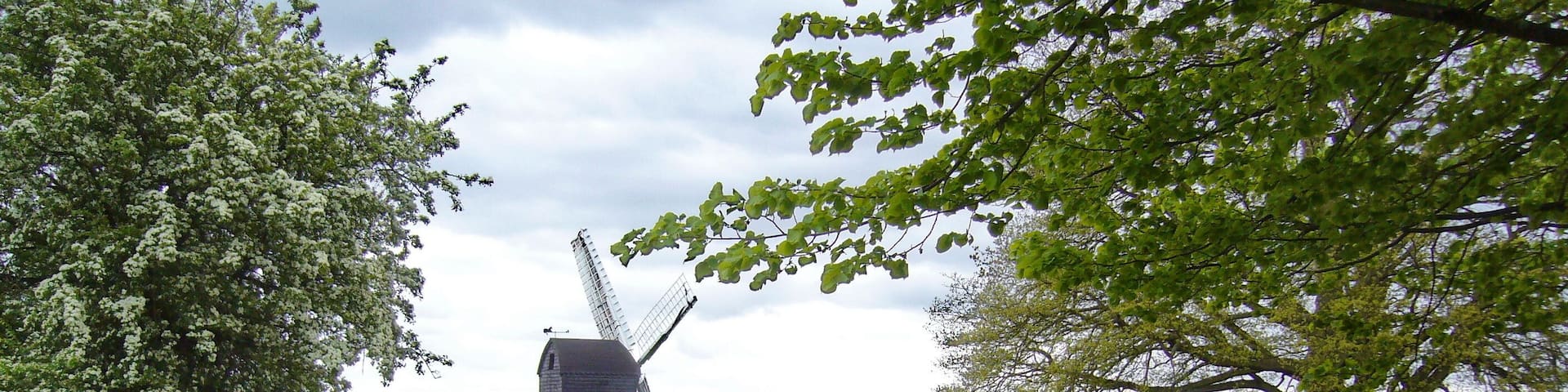 A windmill, a picnic area, and a grassy field with trees.