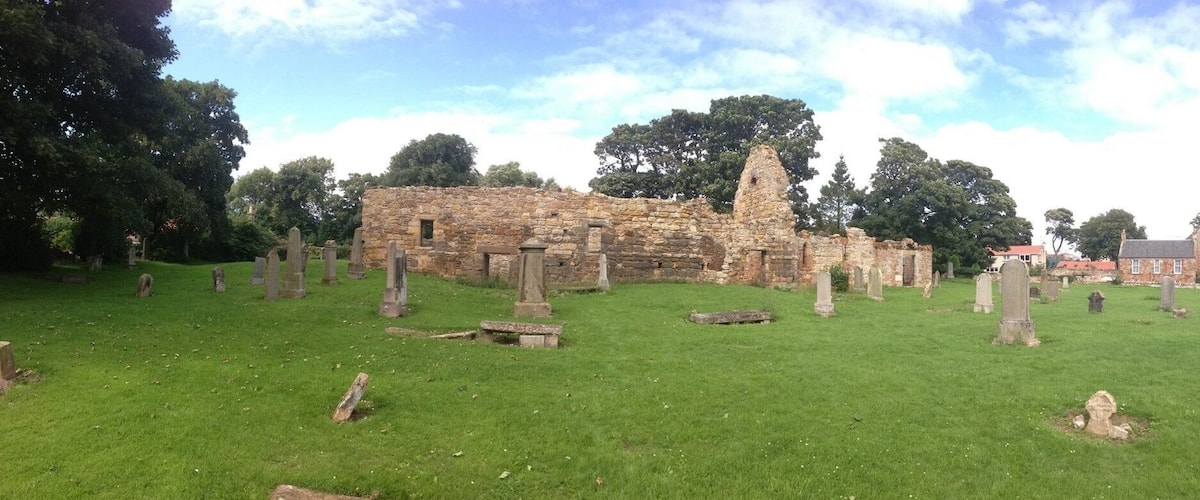 An ancient stone structure surrounded by a cemetery with gravestones.