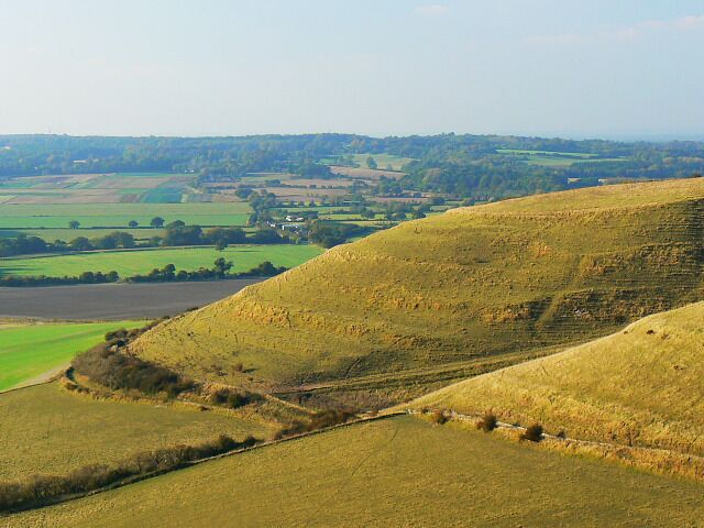 Rolling hills, fields, and a distant village.