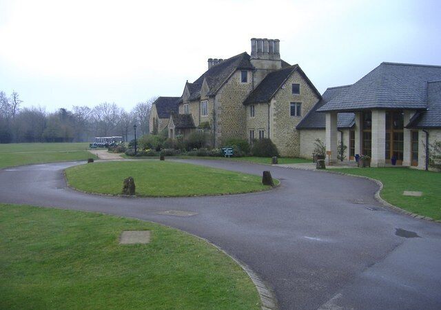 A stone building with a curved driveway and a grassy area.