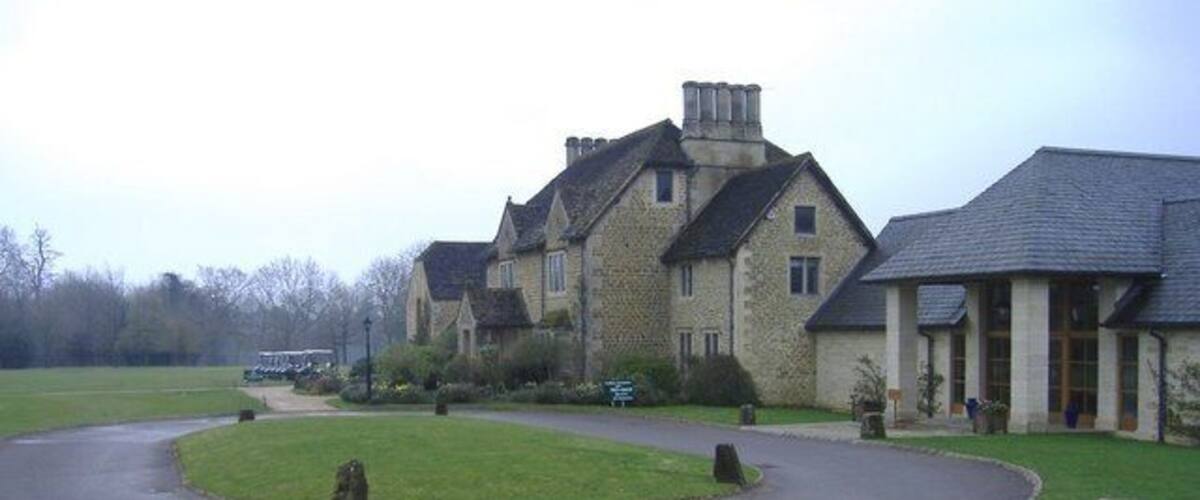 A stone building with a curved driveway and a grassy area.