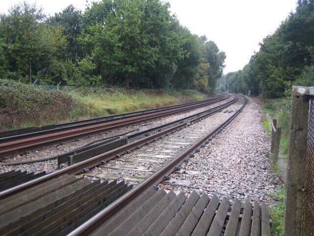 Frimley Junction Once upon a time this was a junction with lines diverging away to the east and west. Nowadays it is just the straight line between Ash Vale and Ascot stations. This view was taken from the pedestrian crossing at the end of The Hatches road, looking in the direction of Frimley station. The standard 750 volt DC offset third rail of the former Southern Railway electric system is clearly visible.